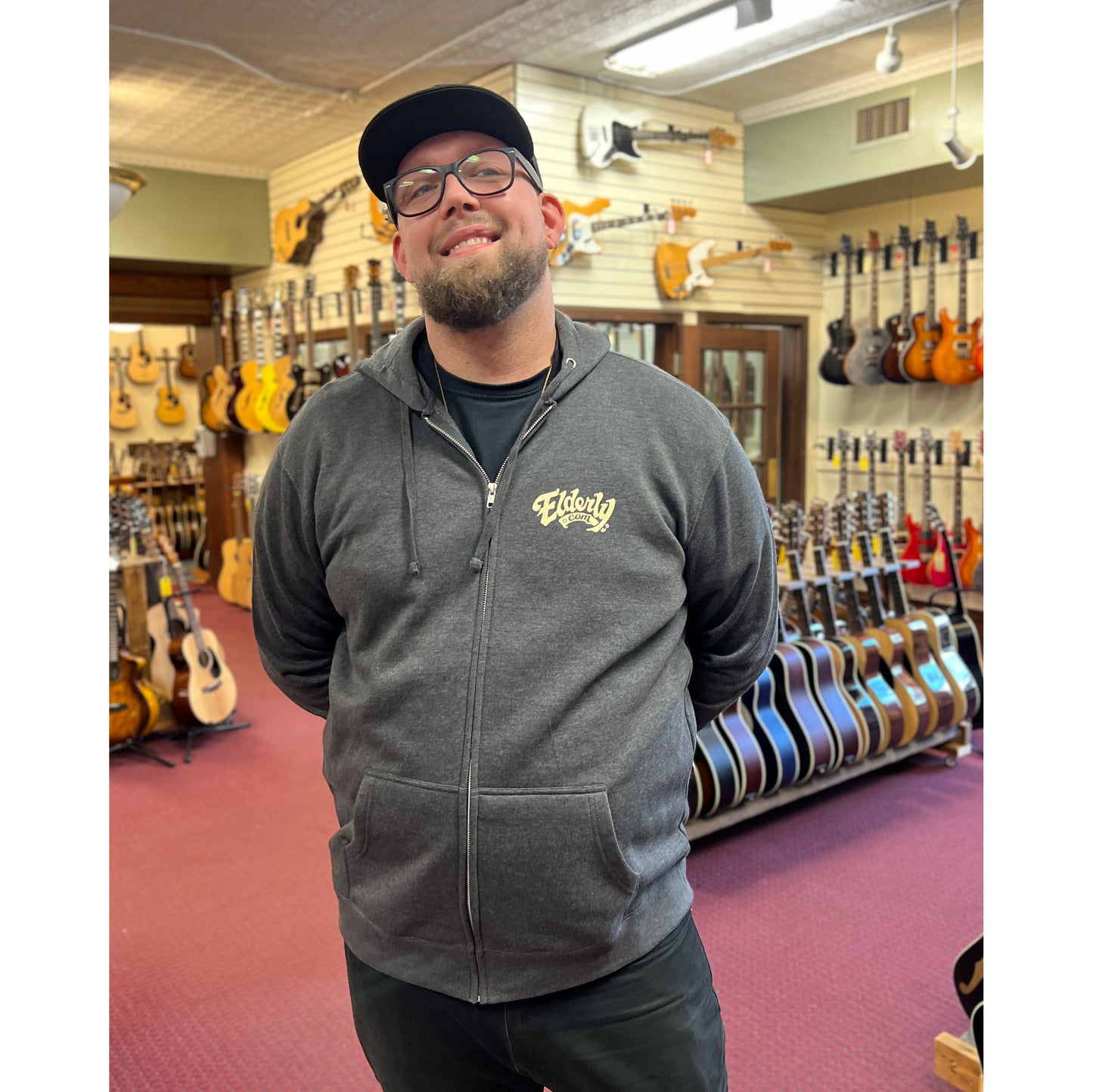 Elderly Staff Member in the Showroom with the Heathered Charcoal Elderly Logo Zip Up Hoodie